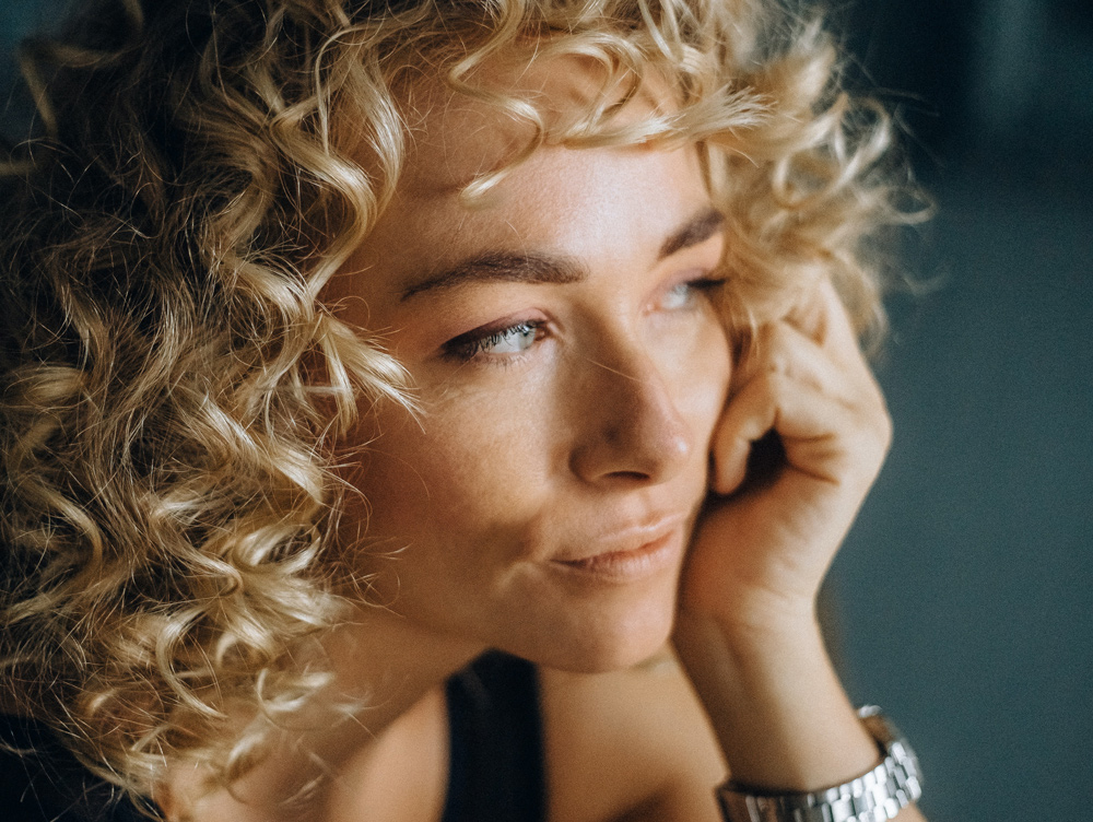 Business Mindset: Pushing Past Perfectionism - Woman thinking, with hand touching her face