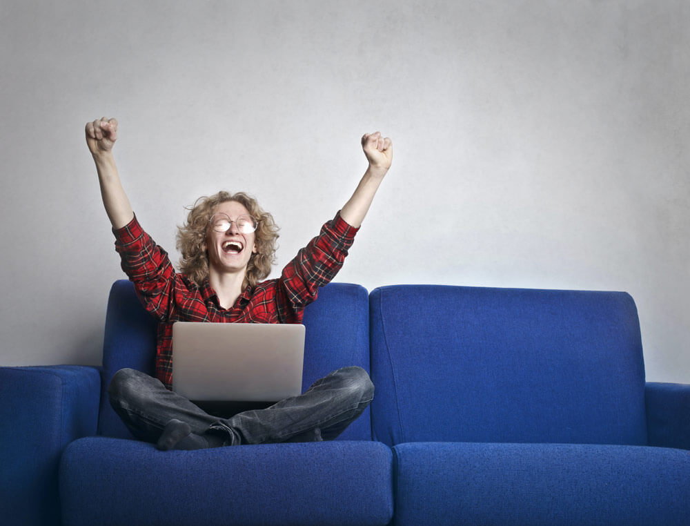 Excited business owner sitting on a couch with arms outstretched