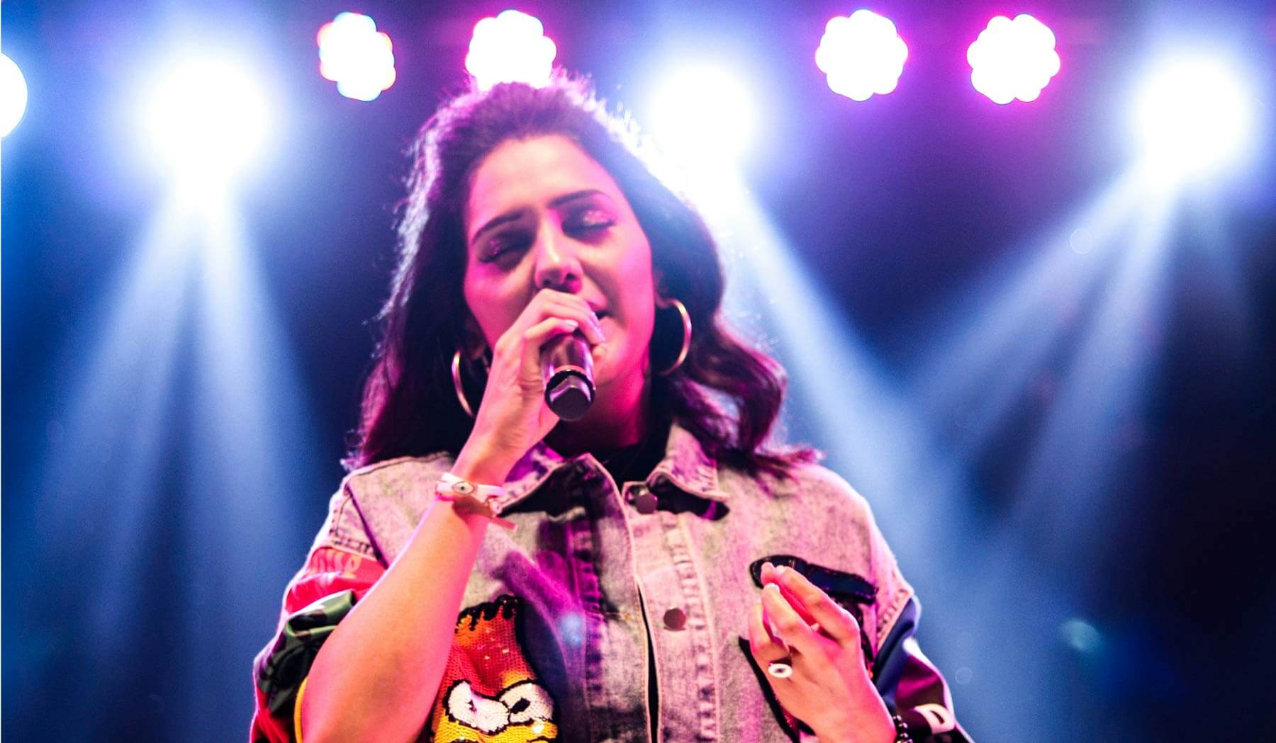 Photo of an woman music artist singing into a microphone - featured image for my music website reviews